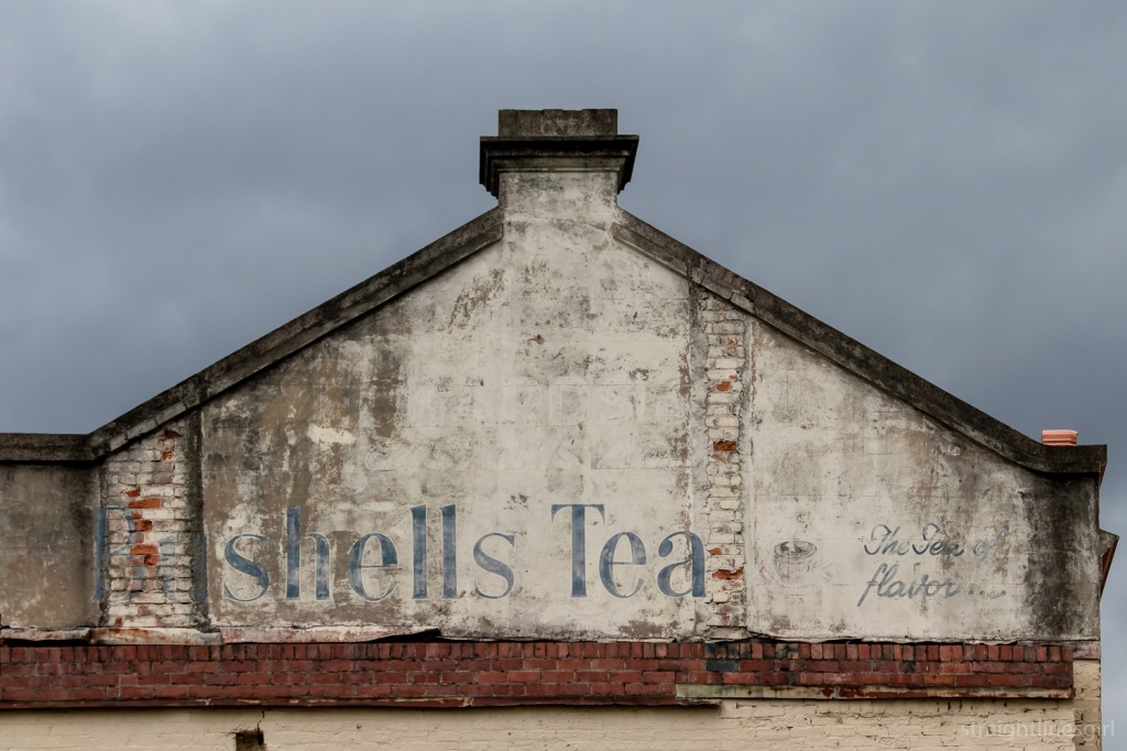 Close up of a wall with the text Bushells Tea in blue text