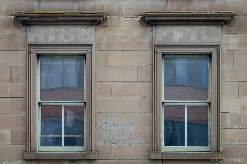 Two windows from  Georgian building with very faint painted worsd Tribute oFfice