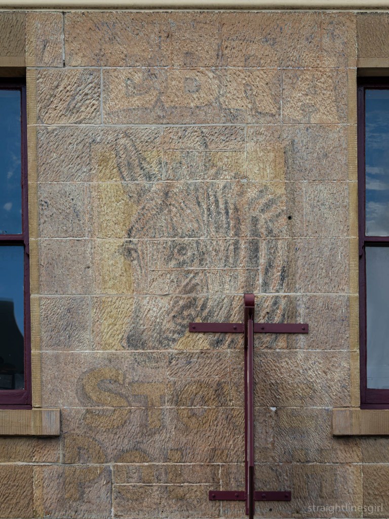 A faded sign painted on a sandstone wall with a picture of a zebra and the words Zebra Stove Polish