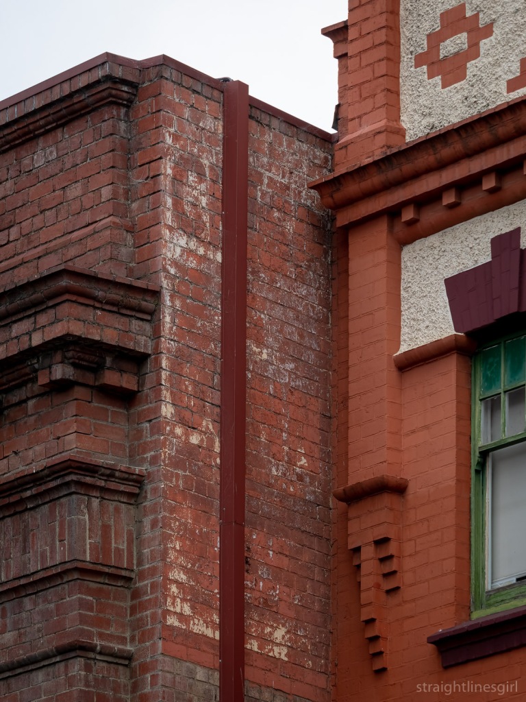 A faded sign on a red brick wall which can just be made out to read "Crisp & Gunn"