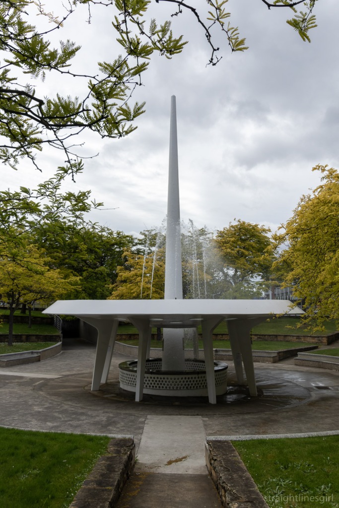 A space-age looking water fountain surrounded by trees