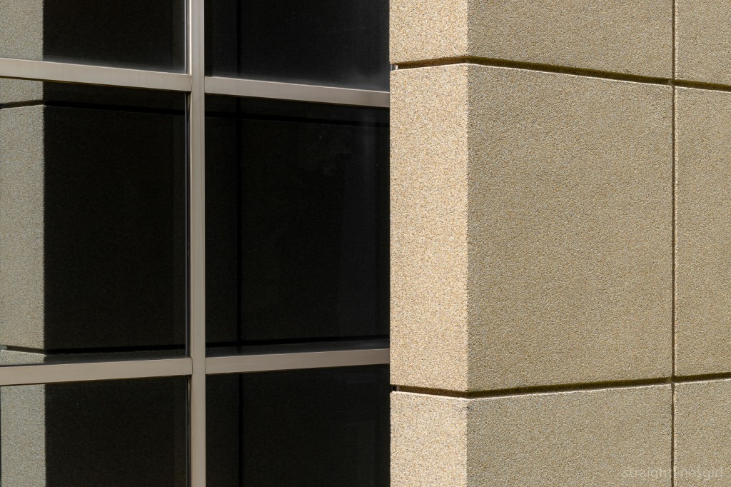 Close up of a pebble-textured wall reflecting in some black windows