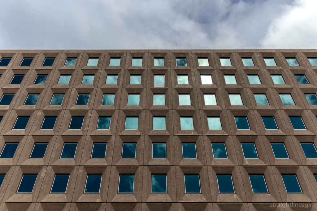 A concrete building facade with several rows of even windows