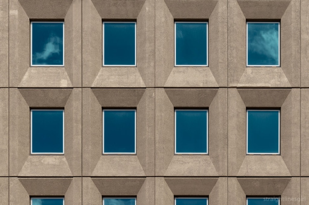 Two rows of four windows in a concrete building facade